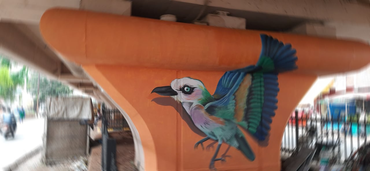 Street art mural of a colourful bird in flight hand-painted on a flyover pillar, GHMC project, Hyderabad