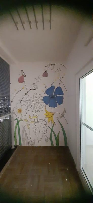 Hand-painted floral mural on a balcony wall in Hyderabad with blue, pink and yellow wildflowers, butterflies and green grass