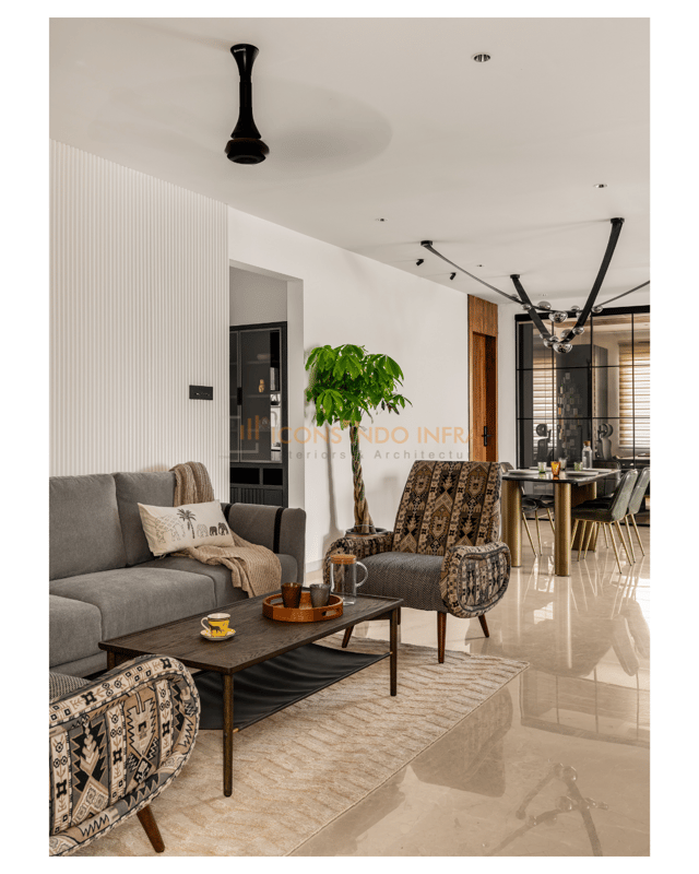 Open living and dining area in Hyderabad with grey sofa, tribal-print armchair, potted plant and starburst dining pendant