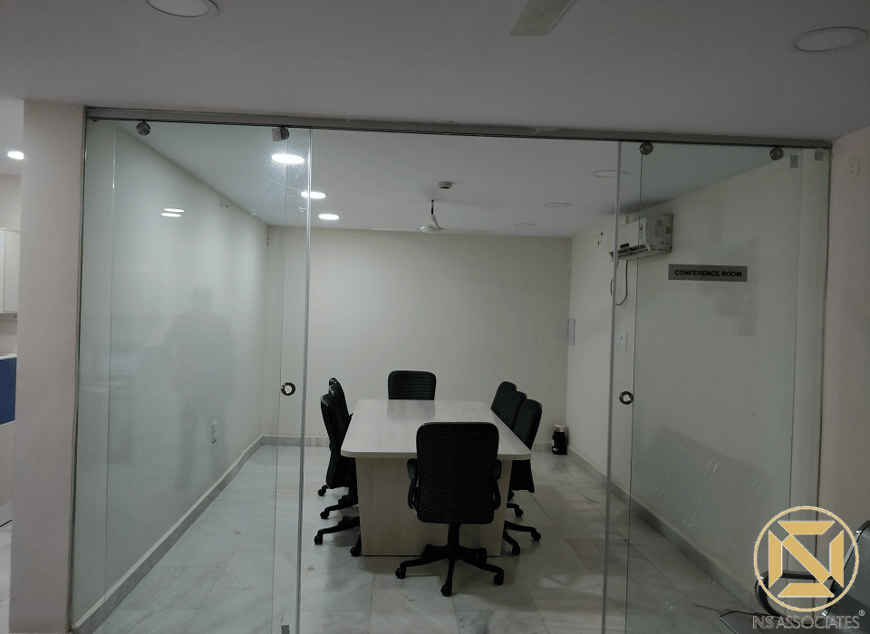 Office conference room enclosed in frameless glass partitions with white table and black chairs, Hyderabad