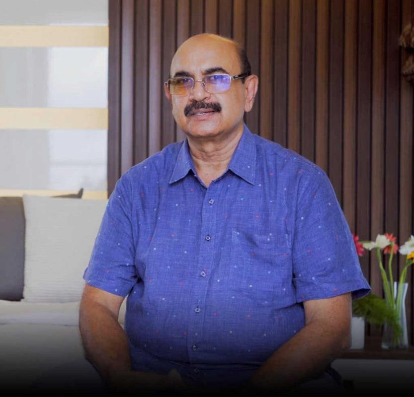 Homeowner in a blue shirt seated before a vertical wood-slat wall and pale sofa during a design testimonial, Hyderabad