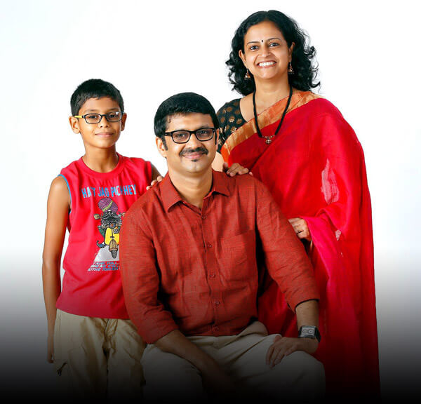 Family portrait of a smiling boy, man in maroon shirt and woman in red saree, Dlife project client photo