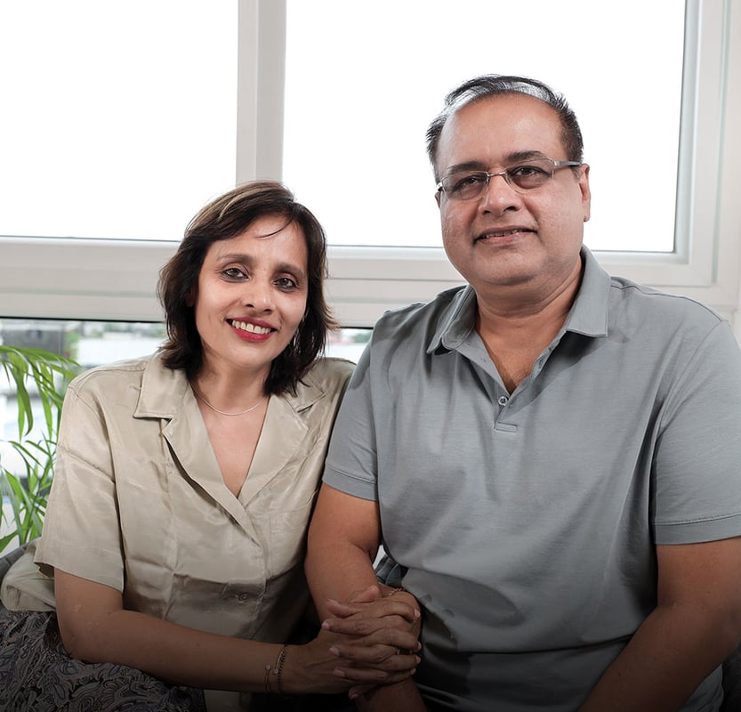 Smiling couple seated together by a bright window, client portrait for a Hyderabad full-home interior project