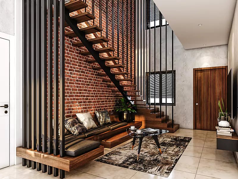 Double-height living area with exposed brick wall, floating wood-tread staircase and leather bench in a rustic duplex, Hyderabad