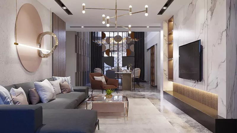 Luxury living room in Hyderabad with grey sectional, marble TV wall, gold linear chandelier and backlit dining beyond