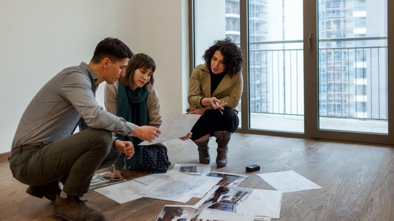 Homeowners reviewing interior design plans with a designer in an empty apartment in India